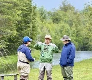 Instructor explicando técnica de lanzamiento junto al río